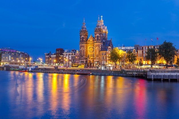 Nachtpanoramablick auf die Stadt von Amsterdam-Kanal, Brücke und Basilika des Heiligen Nikolaus, Holland, Niederlande. Lange Exposition.