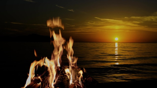 Nachts brennt ein Lagerfeuer vor dem Hintergrund von Bergen und Meer mit hellen Sternen