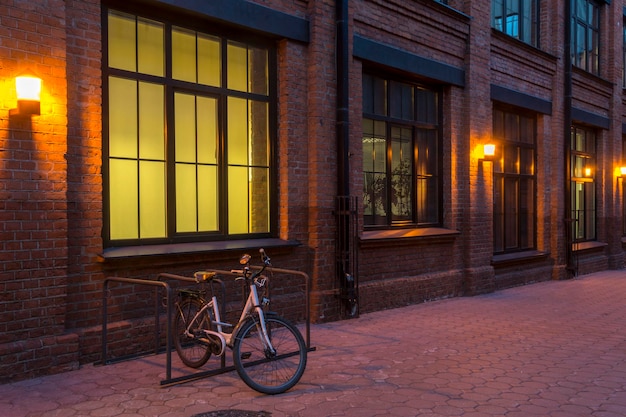 Nachtsicht. Industriegebäude. Bürogebäude im Loft-Stil. Fahrrad auf dem Parkplatz. Haus aus rotem Backstein. Abend