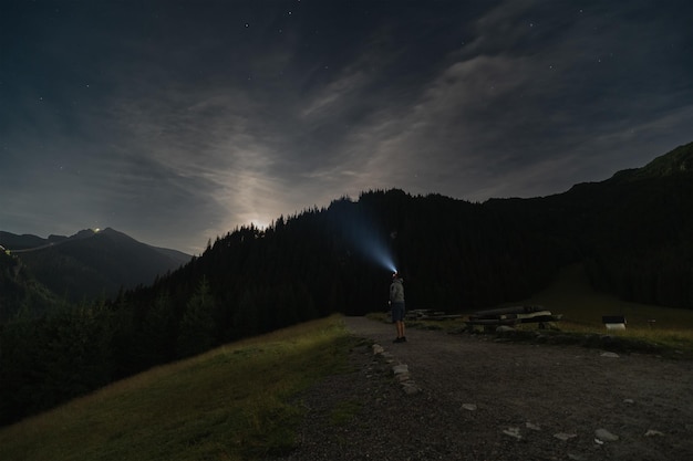 Nachtszene Ein Mann geht nachts mit einer Stirnlampe durch die Berge. Hochwertiges Foto