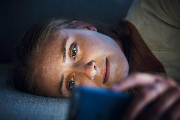 Nachttelefon und junge Frau auf dem Sofa, um Social-Media-Browsing-Internet und Online-Inhalte zu überprüfen