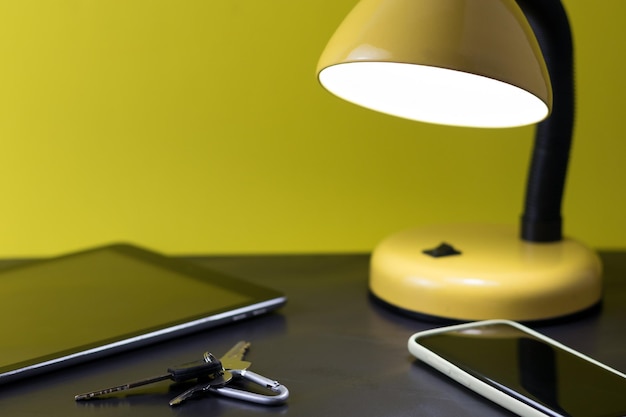 Nachttisch-Detailkonzept mit Tablet-Smartphone-Tasten und einer beleuchteten Lampe