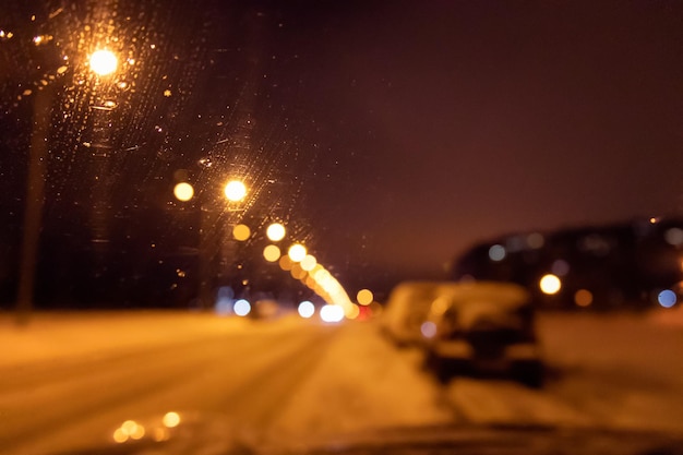Nachtwinterstadtstraße mit Lichtern verschwommener Blick durch die Windschutzscheibe des Autos