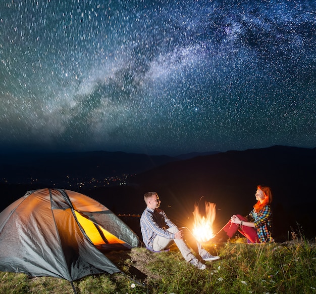 Nachtzeltcamping. Paar Touristen sitzen am Lagerfeuer