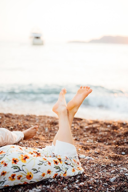 Nackte Füße von Mann und Frau an einem Kiesstrand in der Nähe des Meeres, Nahaufnahme