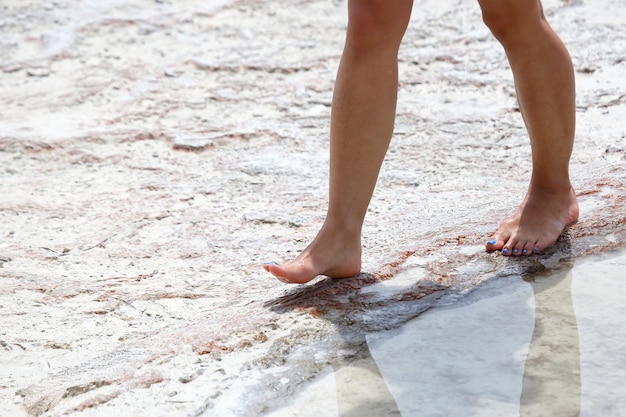 Nackte Füße von Menschen in Jeans, die auf den Travertinen in Pammukale spazieren gehen