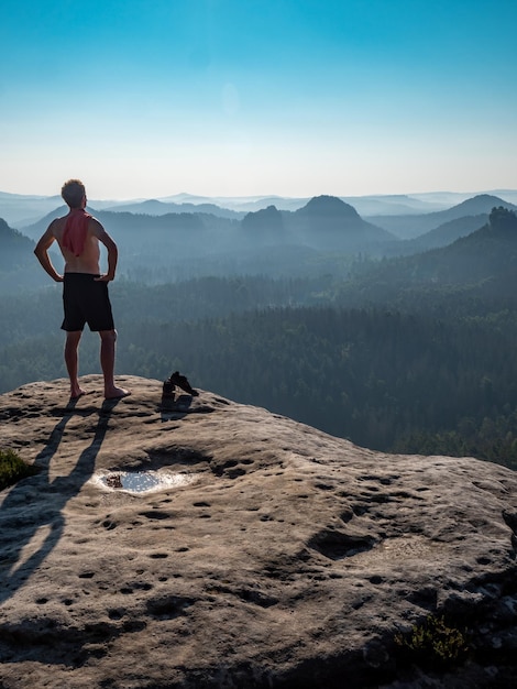 Foto nackter mann mit sportlicher figur am rande eines felsens genießt die aussicht auf die morgenlandschaft