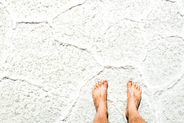 Nackter Mensch barfuß auf Salzoberflächenhintergrund bei Tourausflug in Salar de Uyuni in der Nähe von Isla Incahuasi - Freiheit und unbeschwertes Fernweh-Lifestyle-Konzept, das um die Welt reist - Heller sonniger Filter