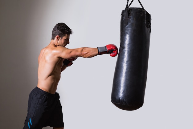 Nackter Oberkörper muskulöser Boxer mit Boxsack