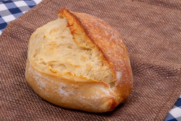 Naco de pão francês tradicional caseiro acabado de cozer sobre fundo de tecido rústico
