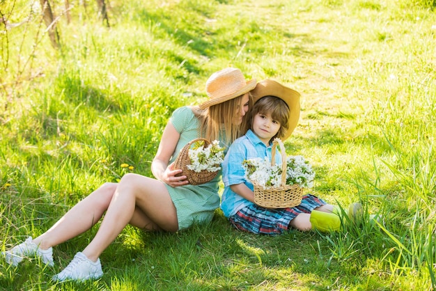 Nada além de família menino pequeno amor mãe férias de verão férias mãe e filho relaxam no parque piquenique na grama verde flor da primavera na cesta mãe e filho no chapéu de palha feliz dia da família dia das mães