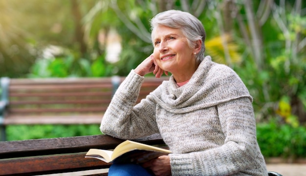 Nada como leer un libro en paz Captura recortada de una alegre anciana leyendo un libro sola afuera en un parque