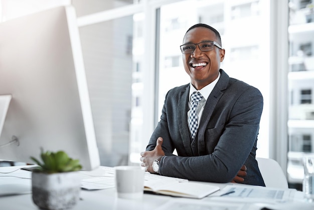 Nada como positividade para aumentar a produtividade Retrato de um jovem empresário trabalhando em sua mesa em um escritório moderno