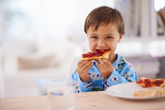 Nada mejor que un buen desayuno Un lindo niño comiendo tostadas con mermelada