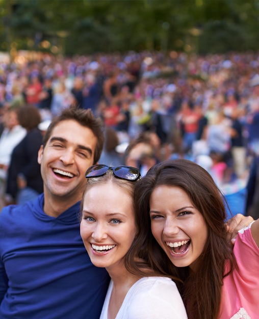 Nada melhor do que um festival com amigos Um grupo de amigos sorridentes juntos em um festival de música com multidão ao fundo