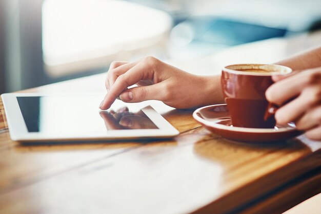 Nada melhor do que um ótimo café e wifi Foto recortada de uma mulher usando um tablet digital em uma cafeteria