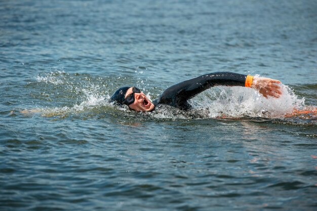 Nadador atleta en traje de neopreno con gafas nada en el agua