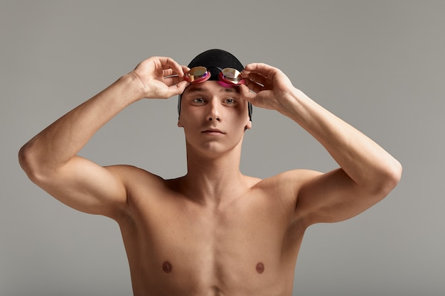 Nadador de boné e máscara, sobre fundo cinza, preparando-se para nadar, close-up, banner publicitário para piscinas, espaço de cópia