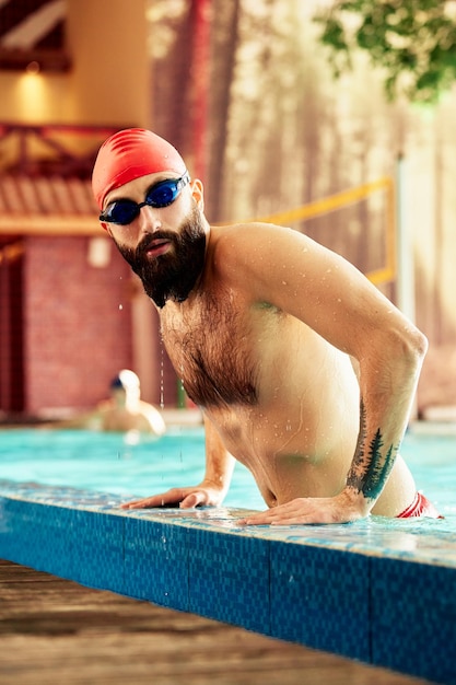 Nadador em pé no trampolim pronto para pular na piscina de competição