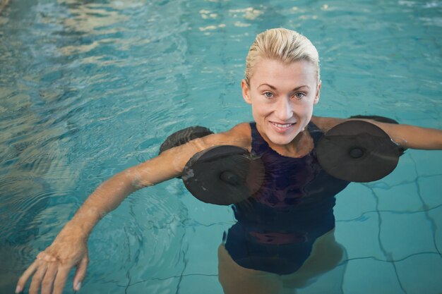 Nadador feminino malhar com halteres de espuma na piscina