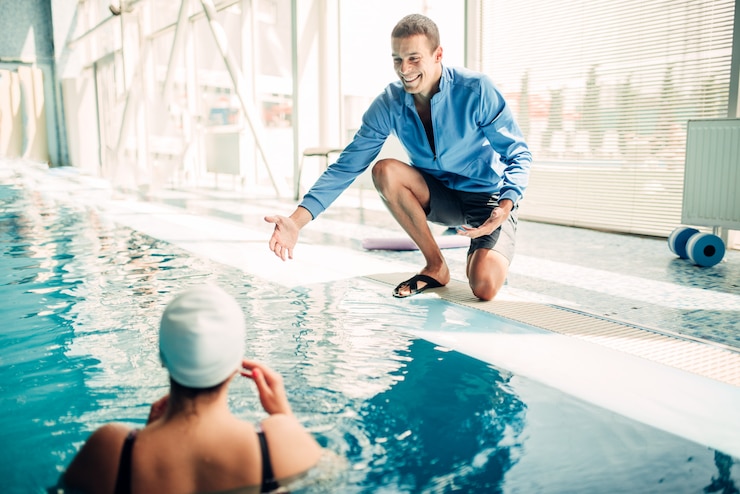 Foto nadador feminino no exercício cap com personal trainer masculino na piscina coberta.