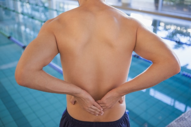 Nadador en forma tocando su espalda junto a la piscina