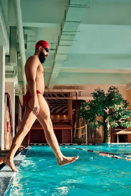 Nadador de pie en trampolín listo para saltar a la piscina de competición