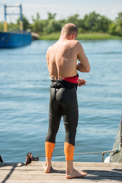 Nadador poniéndose un traje de neopreno en la orilla del río