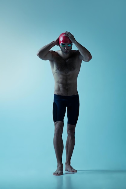 Nadador profesional masculino con sombrero y gafas en movimiento y acción