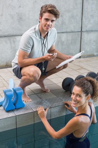 Nadador con su entrenador junto a la piscina sonriendo a la cámara