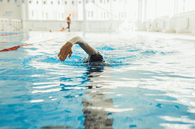 Foto una nadadora profesional en forma haciendo un movimiento de rastreo y nadando en la piscina durante el entrenamiento activo