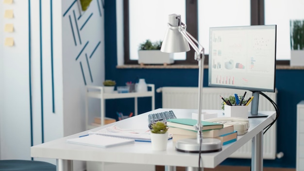 Nadie en el escritorio de la oficina con suministros y estadísticas de marketing en el monitor de la computadora para el crecimiento comercial. Espacio vacío con tecnología moderna e investigación para trabajar en el desarrollo empresarial.