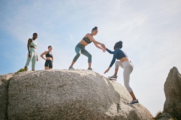 Nadie puede hacerlo sólo. Foto de una mujer que ayuda a su amiga a escalar una roca durante un entrenamiento.