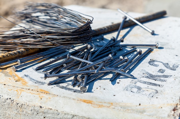 Nägel liegen auf der Betonplatte neben Draht und Stahlstange