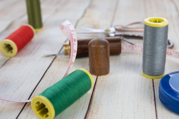 Nähen Hintergrund. Zubehör für Handarbeiten auf Holzuntergrund. Garnrollen, Scheren, Maßband, Nähzubehör. Set für Handarbeit Draufsicht