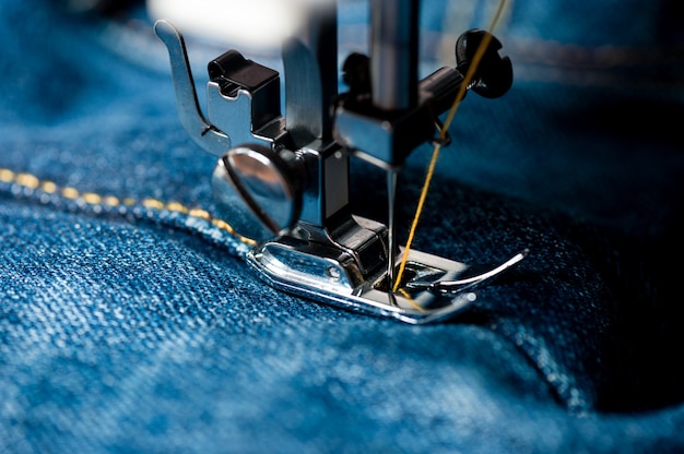 Nähen von Indigo-Denim-Jeans mit Nähmaschine, Bekleidungsindustriekonzept.