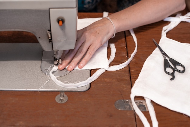 Nähen von medizinischen Schutzgazemasken mit eigenen Händen an einer Nähmaschine, Mangel und Mangel an persönlicher Schutzausrüstung