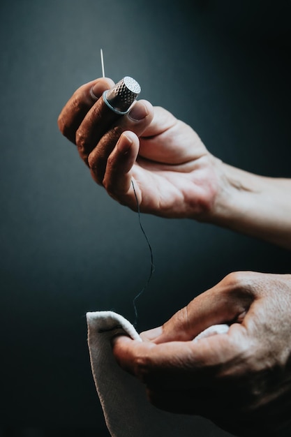 Näherin alte Hasen nähen und arbeiten. Stoff arbeiten und nähen. Lichtvolles Bild, Kopienraum, Fäden in verschiedenen Farben Hintergrund. Stoff mit einem Fingerhut schneiden