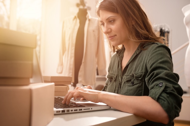 Näherin arbeitet an neuen Kleidungsstücken, die von einem Internetkunden bestellt wurden
