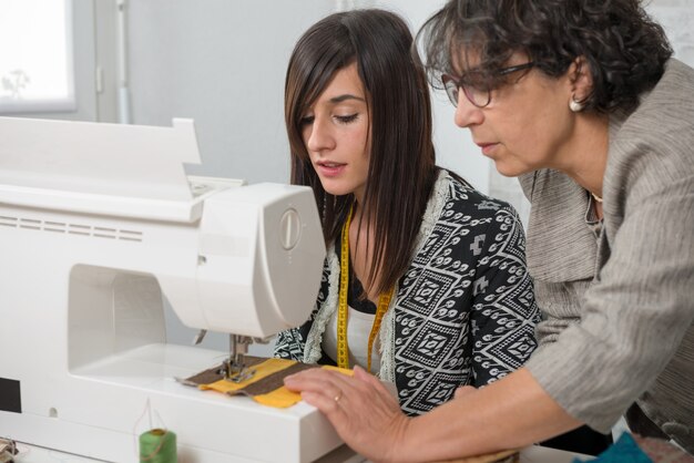 Näherin und ihr lehrling mit nähmaschine