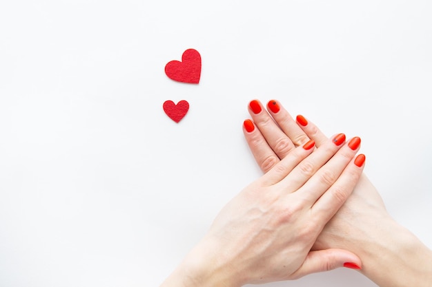 Nagelpflege und Maniküre Schöne weibliche Hände mit einem roten Nagel und einem roten Herz Platz für eine Inschrift Valentinstag