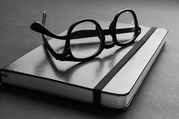 Nahansicht der schwarzen Hipster-Brille auf dem trendigen Notizbuch