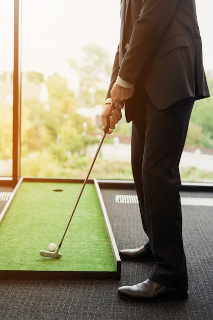 Nahansicht. Ein Mann im Anzug spielt Golf im Büro