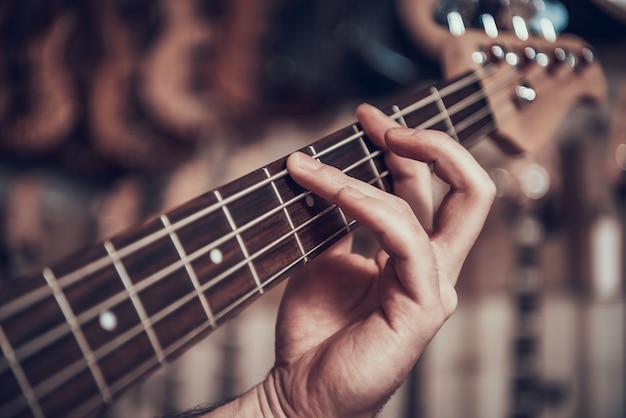 Nahansicht. mannhand klemmt schnüre im bund der e-gitarre fest