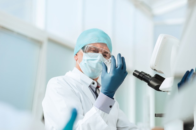 Nahansicht. Wissenschaftler mit einer Ampulle, die an einem Labortisch sitzt. Foto mit einem Kopierraum.