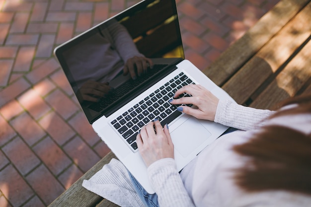 Nahaufnahme abgeschnittene erfolgreiche weibliche Hände auf der Tastatur. Frau, die auf der Bank sitzt und an moderner Laptop-PC-Computer mit leerem leerem Bildschirm in der Straße draußen arbeitet. Mobile Office Freelance-Geschäftskonzept.