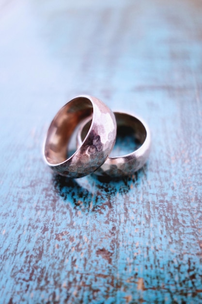 Nahaufnahme alter Hochzeitsringe auf blauem Holztisch