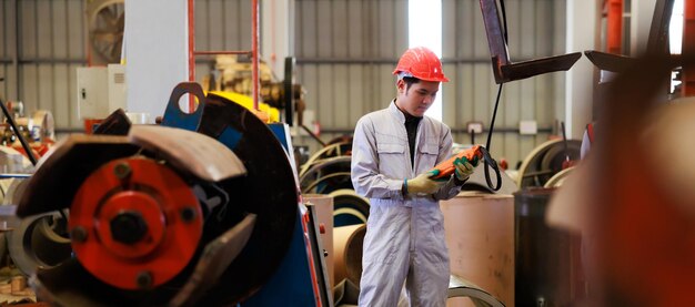 Nahaufnahme Arbeiterhände steuern Innenlaufkran, um Metallkonstruktionsobjekt auf Blechfabrik anzuheben