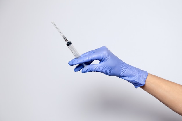 Nahaufnahme Arzthand in Gummi lila Handschuh hält transparente Spritze mit geschlossener Kappe