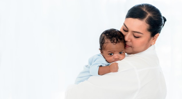 Nahaufnahme auf dem Gesicht des 1 Monate alten neugeborenen Sohnes auf der Schulter der Mutter mit weißem Hintergrund